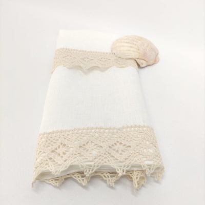 Toalha branca com renda bege e uma concha em fundo branco