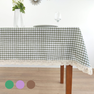 Toalha de mesa xadrez verde e branca com borda de renda creme sobre mesa de madeira