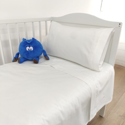 Berço branco com roupa de cama branca e brinquedo de pelúcia azul