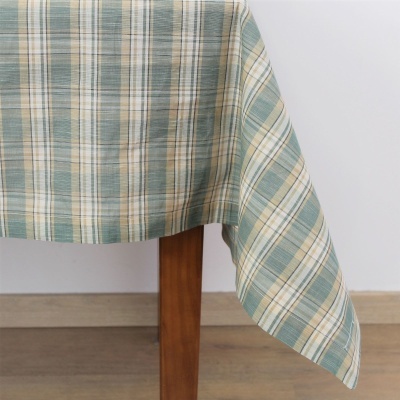 Toalha de mesa de tecido xadrez em verde, bege e branco numa mesa de madeira