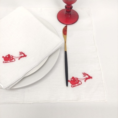 Jogo americano e guardanapo brancos com bordado vermelho de trenó e rena, faca preta e dourada, copo vermelho e prato branco