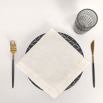 Mesa posta com talheres, guardanapo branco, prato com padrão preto e branco e copo transparente.