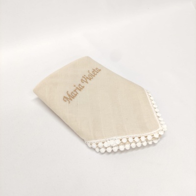Guardanapo de tecido bege com bordado e pompons na borda