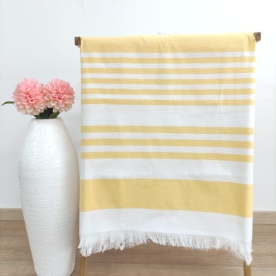 Toalha de riscas amarelas e brancas pendurada com vaso branco e flores cor-de-rosa