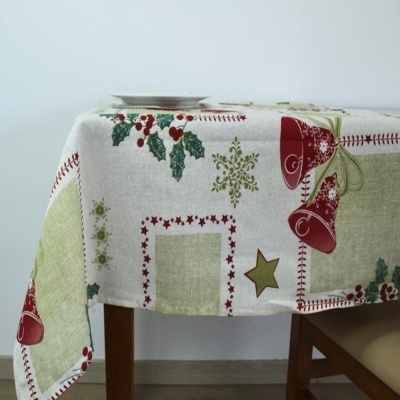 Toalha de mesa natalícia branca com motivos vermelhos e verdes sobre mesa de madeira