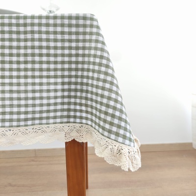 Toalha de mesa xadrez verde e branco com renda bege na borda sobre mesa de madeira