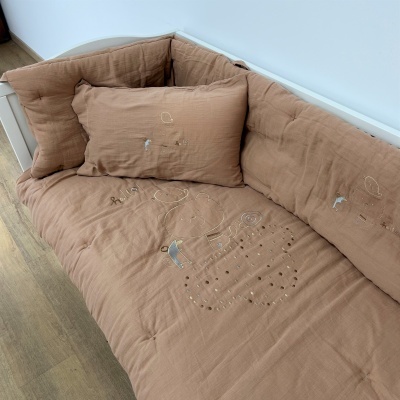 Sofá castanho claro com almofada e bordados, em sala com chão de madeira