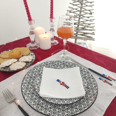 Conjunto de pratos e copo sobre toalha branca e vermelha com velas acesas