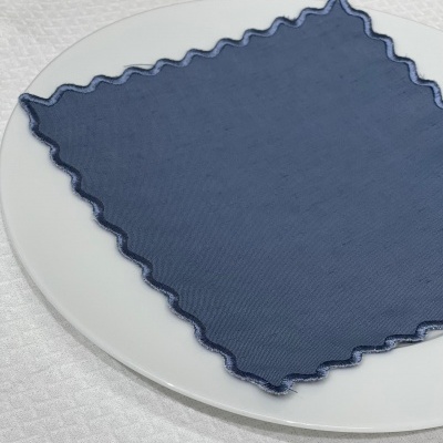 Guardanapo azul escuro com bordas onduladas sobre prato branco