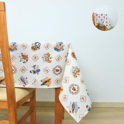 Toalha de mesa branca com padrão colorido de barcos e flores sobre mesa de madeira