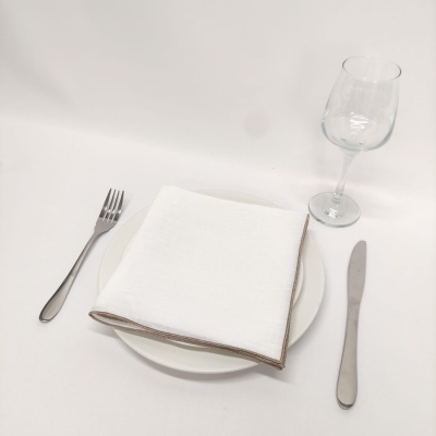 Mesa posta com prato branco, guardanapo branco, talheres de metal e copo de vinho de vidro