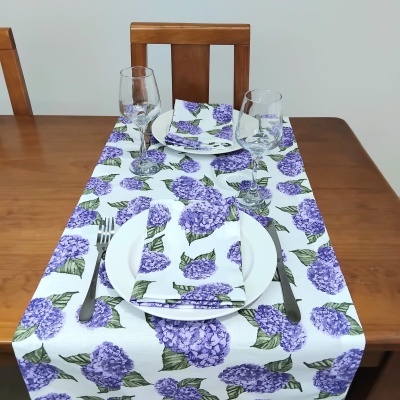 Mesa de jantar com toalha e guardanapos com padrão floral lilás e verde