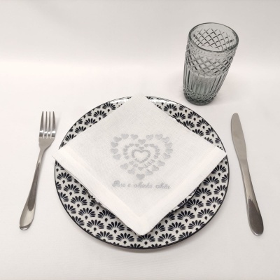 Conjunto de prato, guardanapo com coração e texto, talheres e copo sobre mesa branca