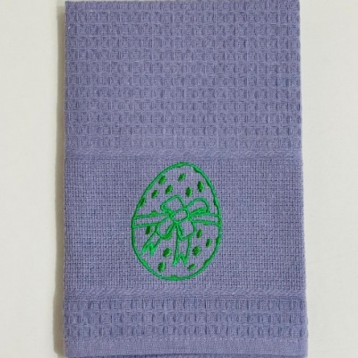 Toalha lilás com bordado verde de ovo decorado.