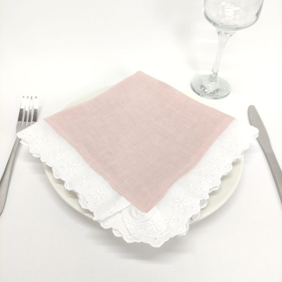 Guardanapos rosa e branco sobre prato branco com talheres e copo de vinho