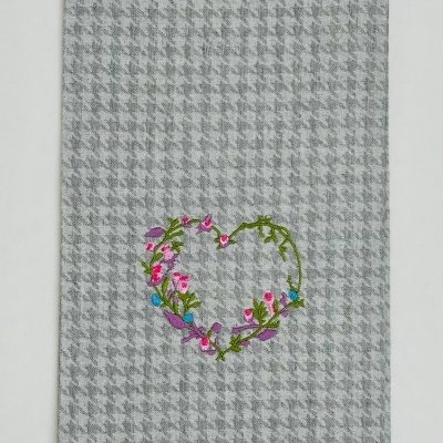 Pano de tecido cinzento com bordado de coração floral colorido