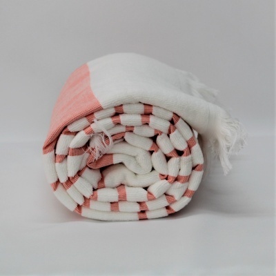 Manta enrolada com padrão de riscas branco e rosa claro e franjas