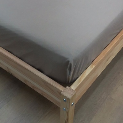 Canto de cama de madeira com colchão cinza e chão de madeira