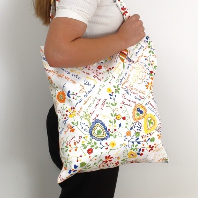 Bolsa de tecido branco com padrão bordado colorido e alças com o mesmo padrão.