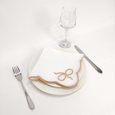 Guarda-napo branco com borda castanha num prato branco com talheres e copo