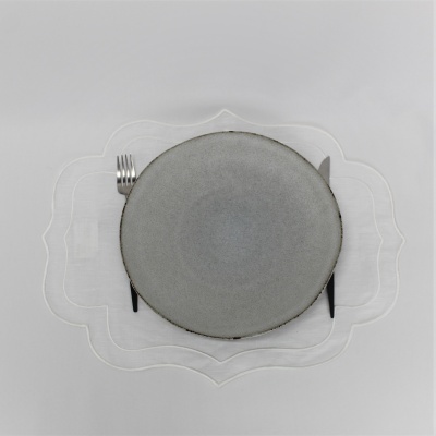 Prato cinza redondo com garfo e faca prateados em individual transparente ornamentado