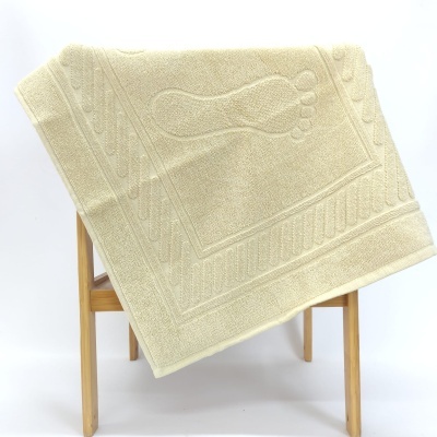 Toalha bege com relevo de pegada pendurada numa estrutura de madeira