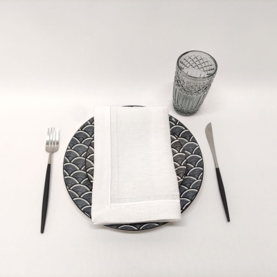 Conjunto de pratos, talheres e copo com padrão geométrico sobre superfície branca