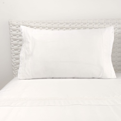 Travesseiro branco com fronha e lençol branco em cama acolchoada