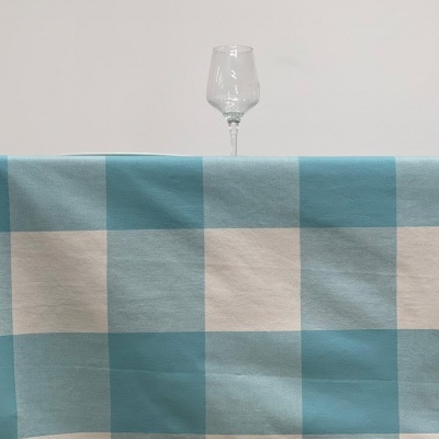 Toalha de mesa azul e branca com taça de vidro sobre mesa de madeira