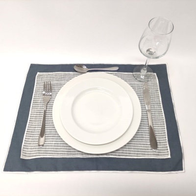 Conjunto de jantar com pratos brancos, talheres inox, guardanapo riscado e taça de vidro