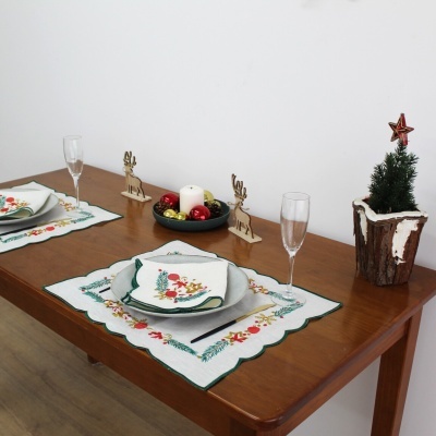 Mesa de madeira posta para Natal com pratos cinza, enfeites natalícios e pequeno pinheiro decorativo.