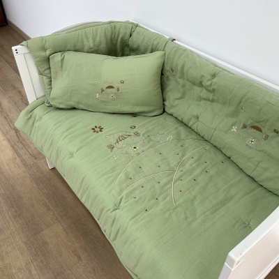Sofá-cama branco com almofadões e almofada decorativa verde com bordados de animais e flores