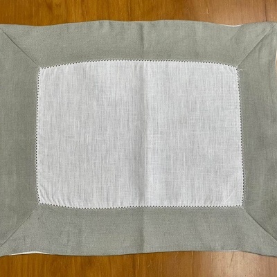 Jogo americano retangular branco com borda cinza sobre mesa de madeira