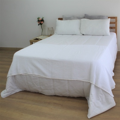 Cama de casal com edredão branco e manta branca com padrão quadrícula