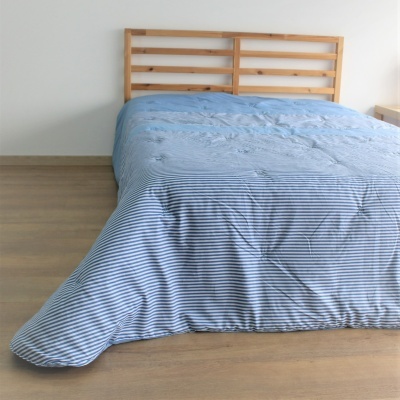 Cama de madeira com edredão azul claro e riscas brancas