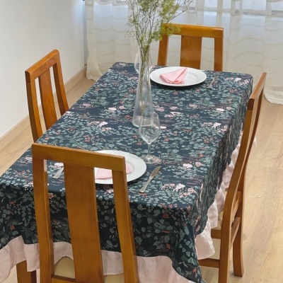 Mesa de madeira com toalha floral e cadeiras, arranjo de flores secas no centro