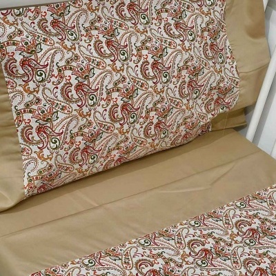 Jogo de cama bege com padrão floral e arabesco em berço branco