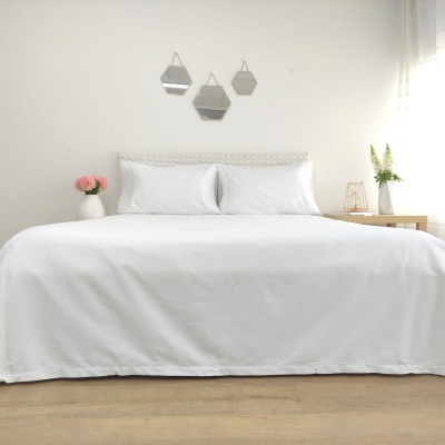 Cama com roupa de cama branca e decoração minimalista em quarto claro
