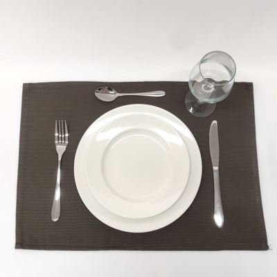 Mesa posta com prato branco, talheres em metal, copo e base castanha.