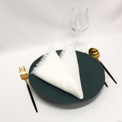 Conjunto de jantar com prato verde escuro, guardanapo branco, talheres dourados e taça de vidro