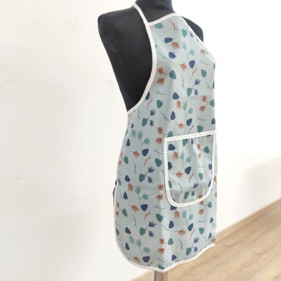 Avental cinza claro com padrão de folhas coloridas num manequim preto