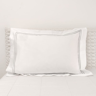 Almofada branca com linhas cinzentas numa cama