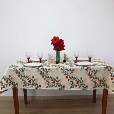 Mesa posta para quatro pessoas com toalha decorada, copos, pratos, vaso com flores vermelhas e decoração de renas.