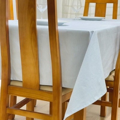 Mesa de madeira com toalha branca riscada azul e cadeiras de madeira clara
