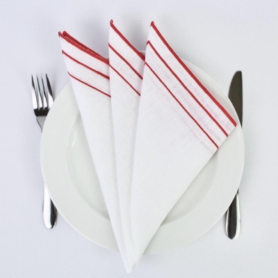 Guardanapos brancos com riscas vermelhas em prato branco com talheres
