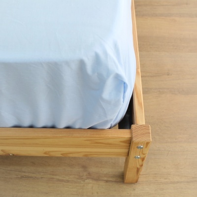 Canto de cama com estrutura de madeira clara e lençol azul claro