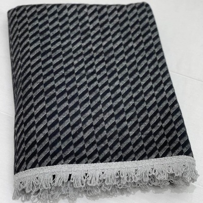 Manta cinza e preta com padrão geométrico e franjas brancas