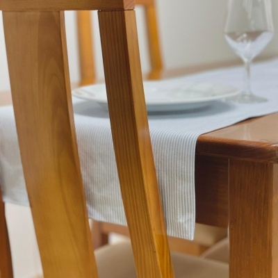 Cadeira de madeira clara e mesa com toalha branca e prato