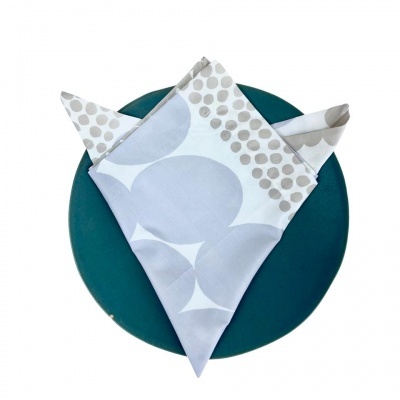 Guardanapo tecido com padrão cinzento e bege em prato verde-azulado