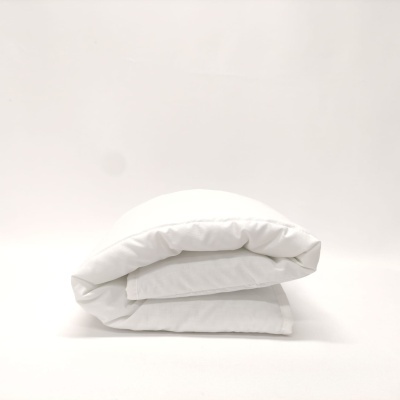 Edredão branco dobrado sobre superfície branca